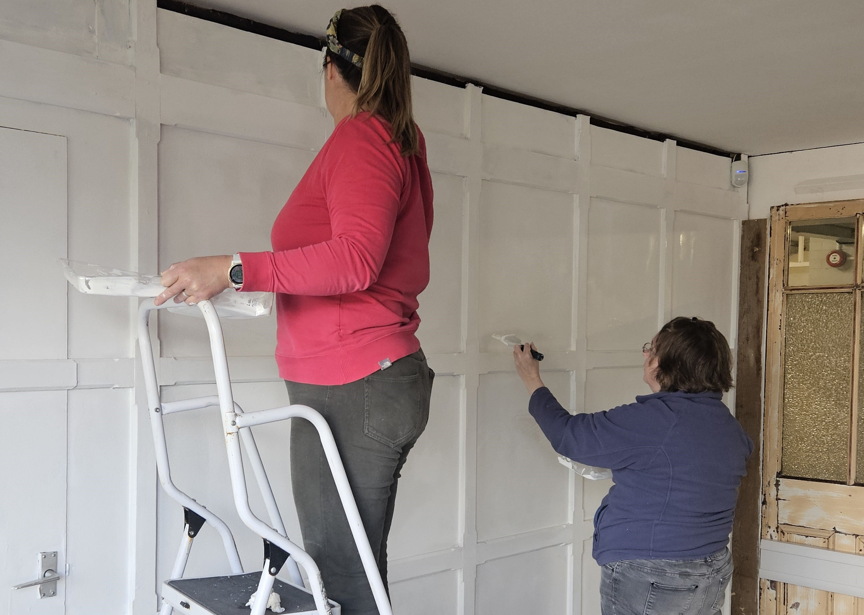 Two NHS staff members painting panels on a wall