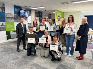 Thriving students smile at he camera while holding their graduation certificates